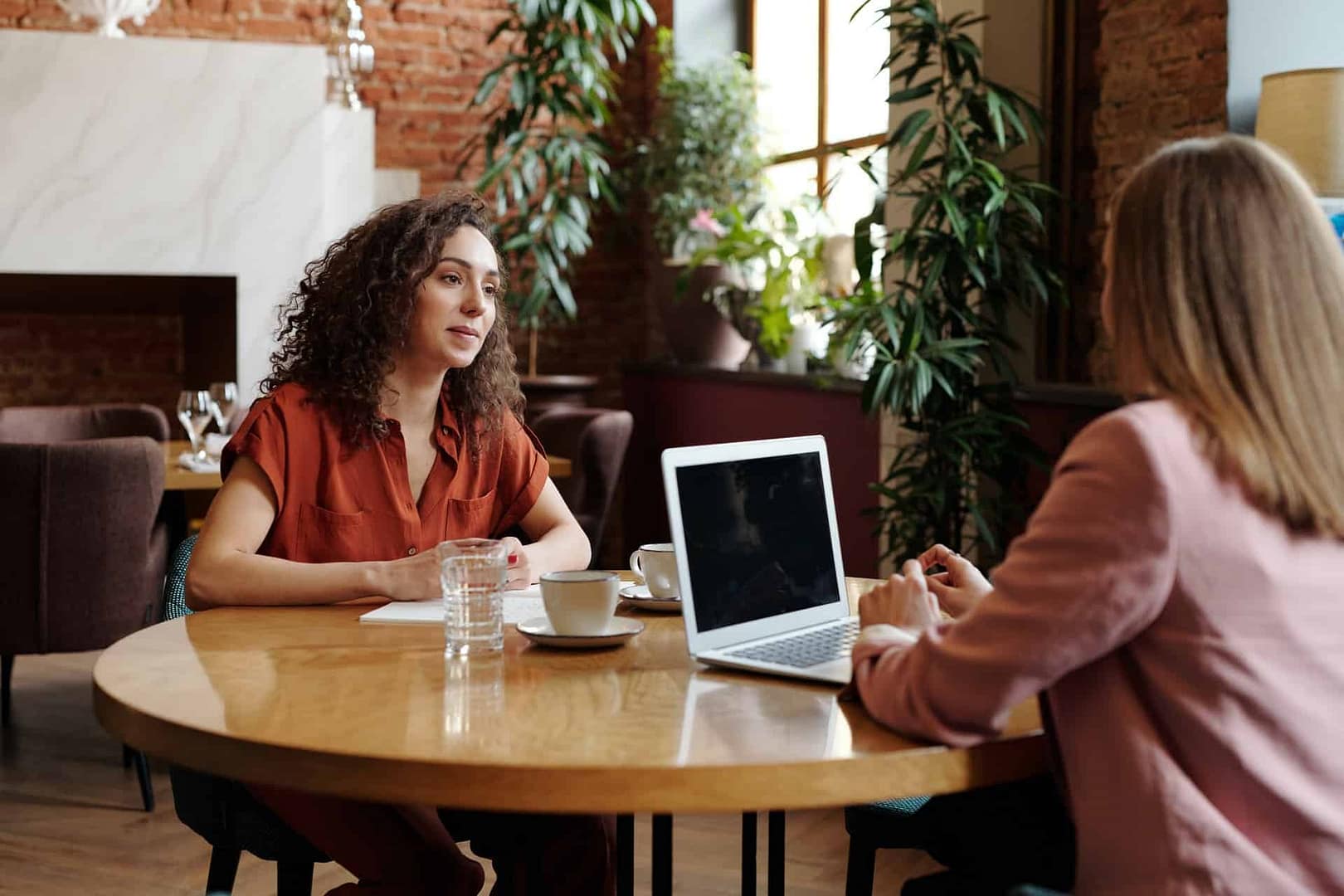 two women meeting using a pen and paper and laptop