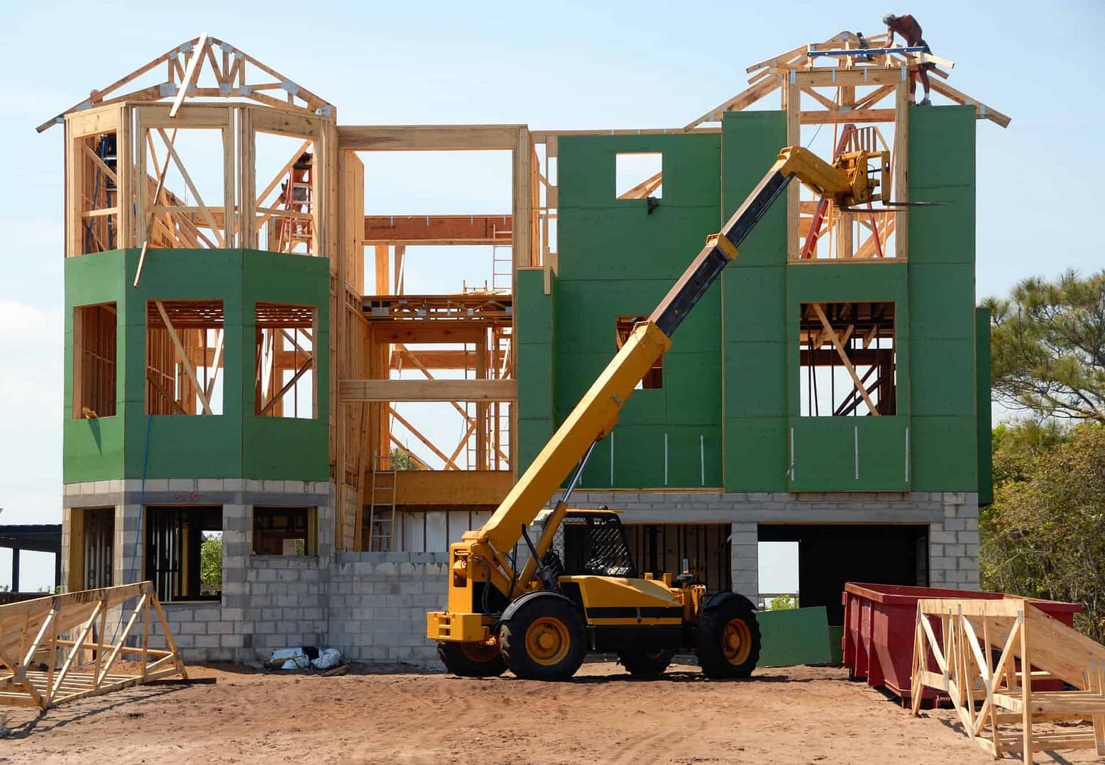 wooden house frame with yellow forklift in front